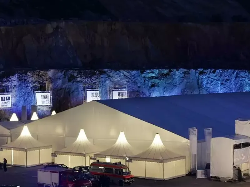 Illuminated clear span tent at night with additional smaller canopy structures.