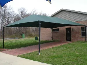 Green freestanding shade structure installed over a walkway.
