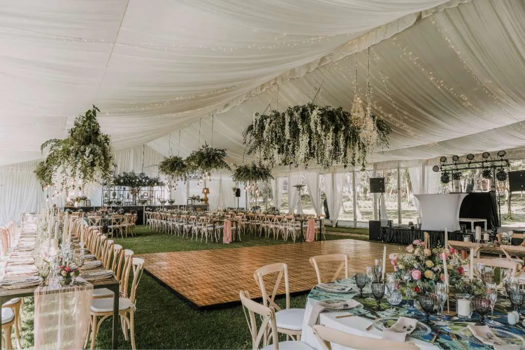 Elegant tent interior decorated with drapery and floral arrangements for an event.