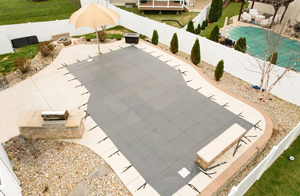 Backyard swimming pool secured with a tan safety cover.