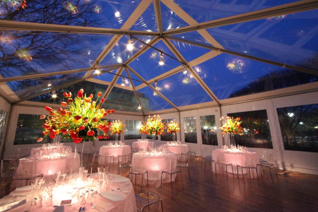 Large clear top tent set up for a corporate or party event, providing open space for dining, dancing, and entertainment while displaying the sky above.