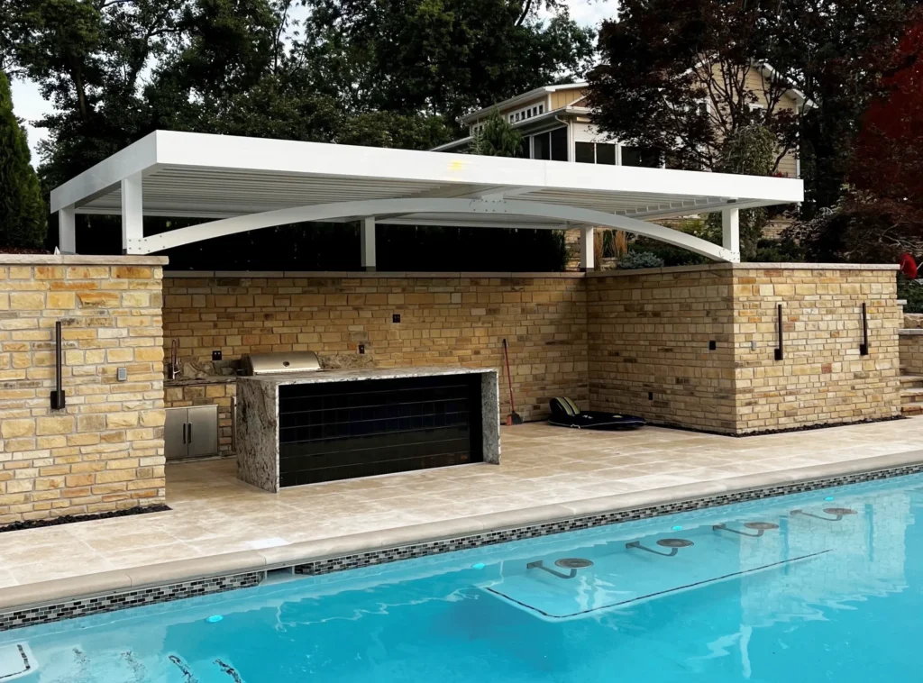 Poolside pergola covering a modern outdoor grill and kitchen area.