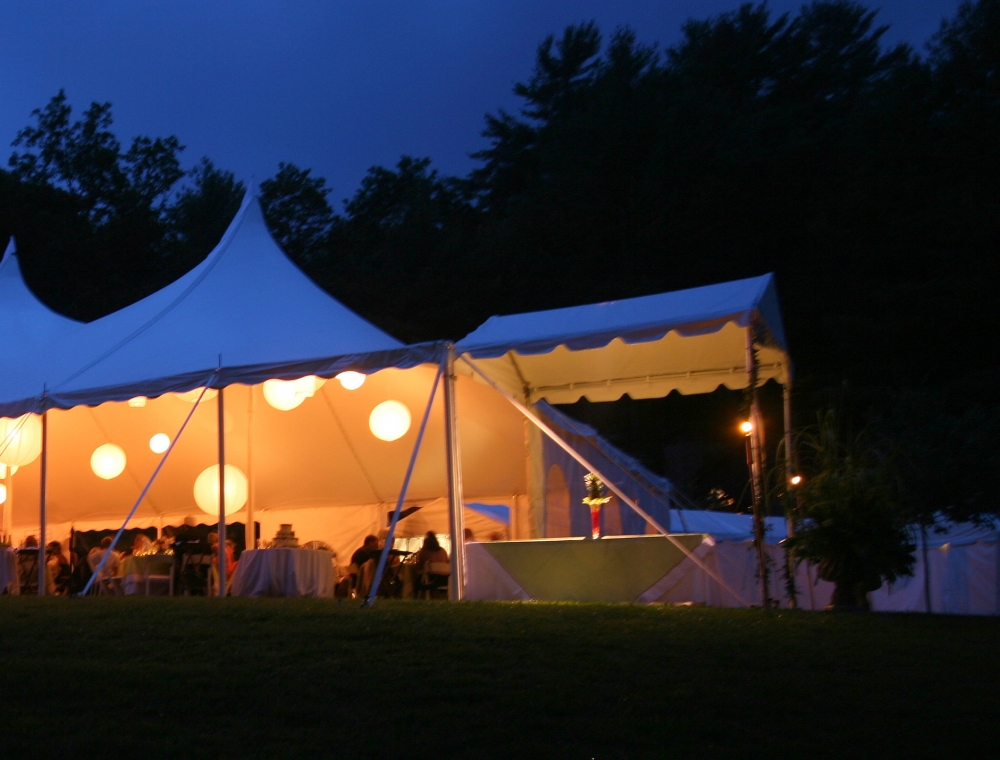 Elegant high-peak event tent at night with glowing lanterns, creating a cozy and festive ambiance for weddings and receptions.