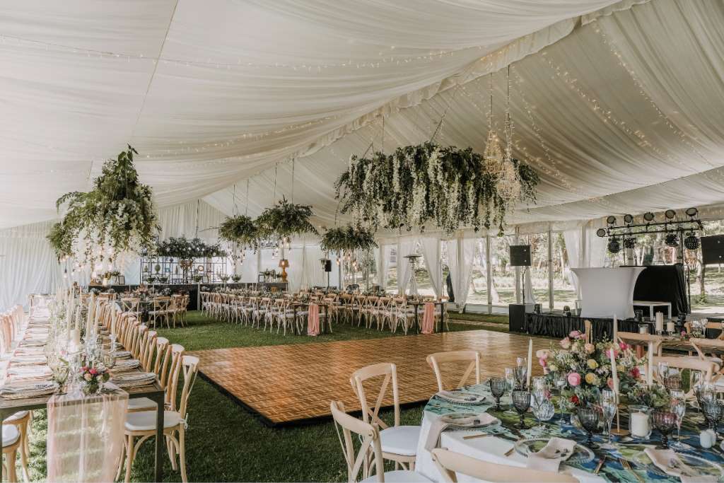 Elegant tent interior decorated with drapery and floral arrangements for an event.