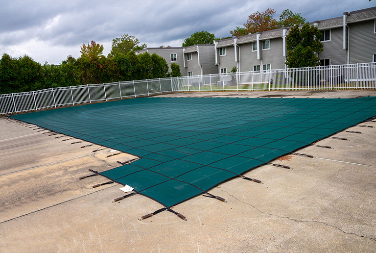 Rectangular swimming pool protected by a dark green mesh cover.