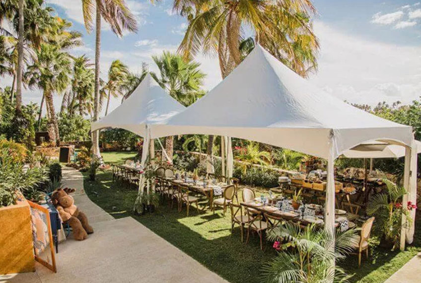 White frame tent with open sides covering an outdoor dining area.