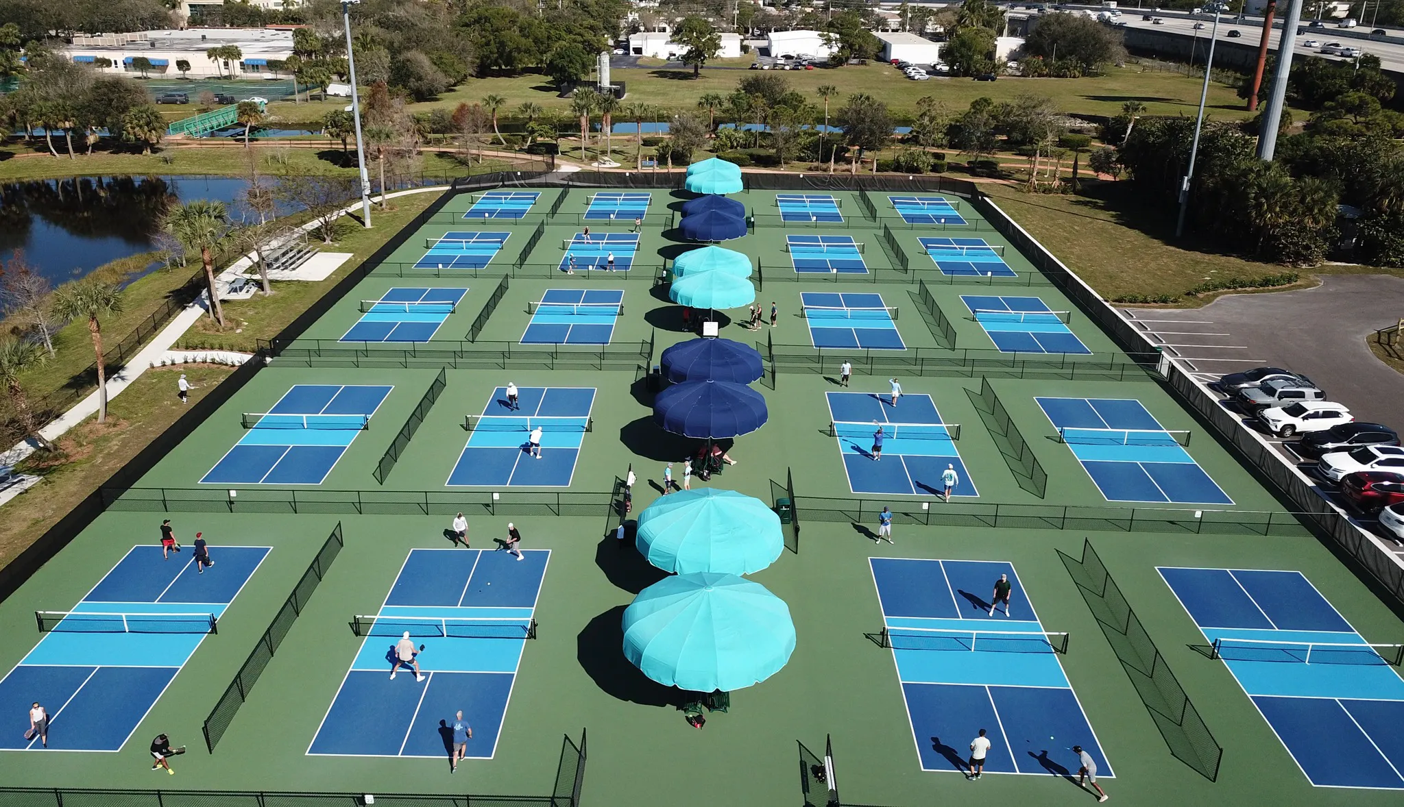 Tennis courts lined with blue canopy shades and light poles.