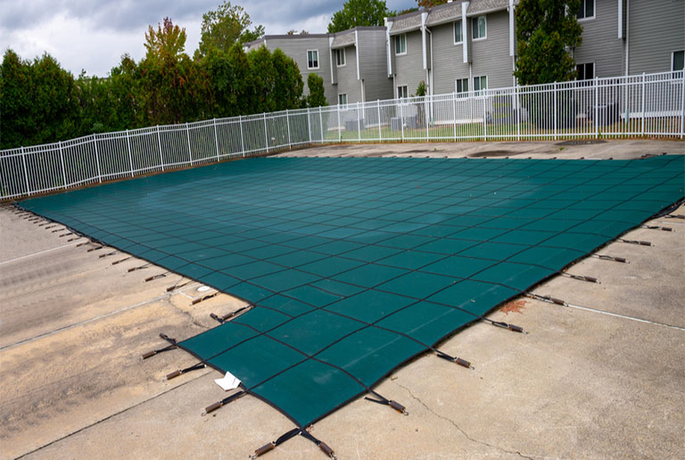 Anchor Industries solid pool cover protecting backyard swimming pool from debris and weather.