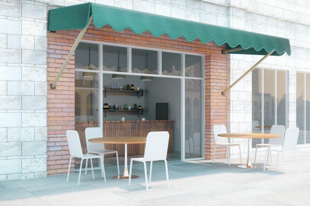 Small café with a green scalloped awning and white chairs outside.