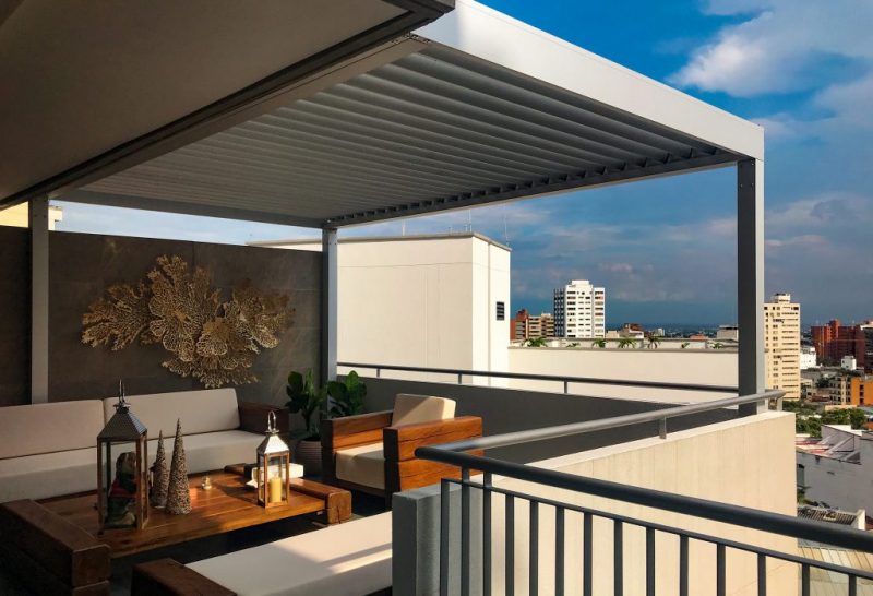 Luxurious rooftop terrace with a motorized louvered pergola, creating a shaded outdoor living space with city views. Premium retractable patio cover.
