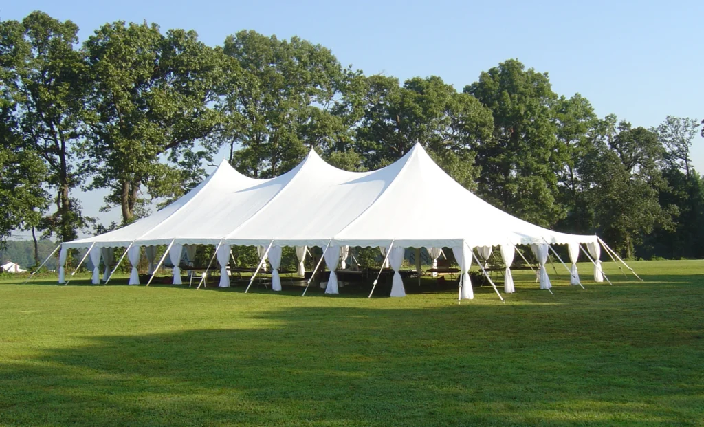 Large white Anchor Industries pole tents with multiple peaks in a park setting
