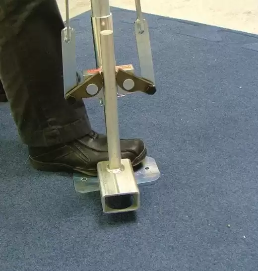 Tent anchor tool in use – close-up of specialized equipment securing a tent pole.