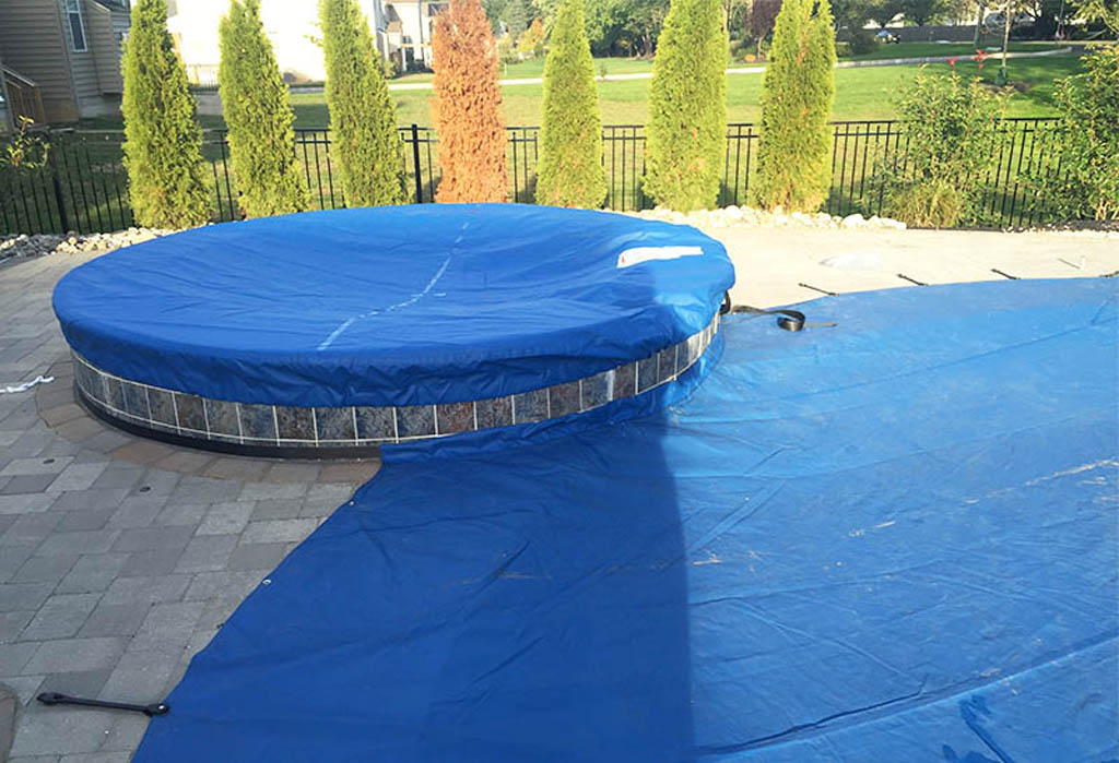 Round above-ground pool protected with a blue safety cover.