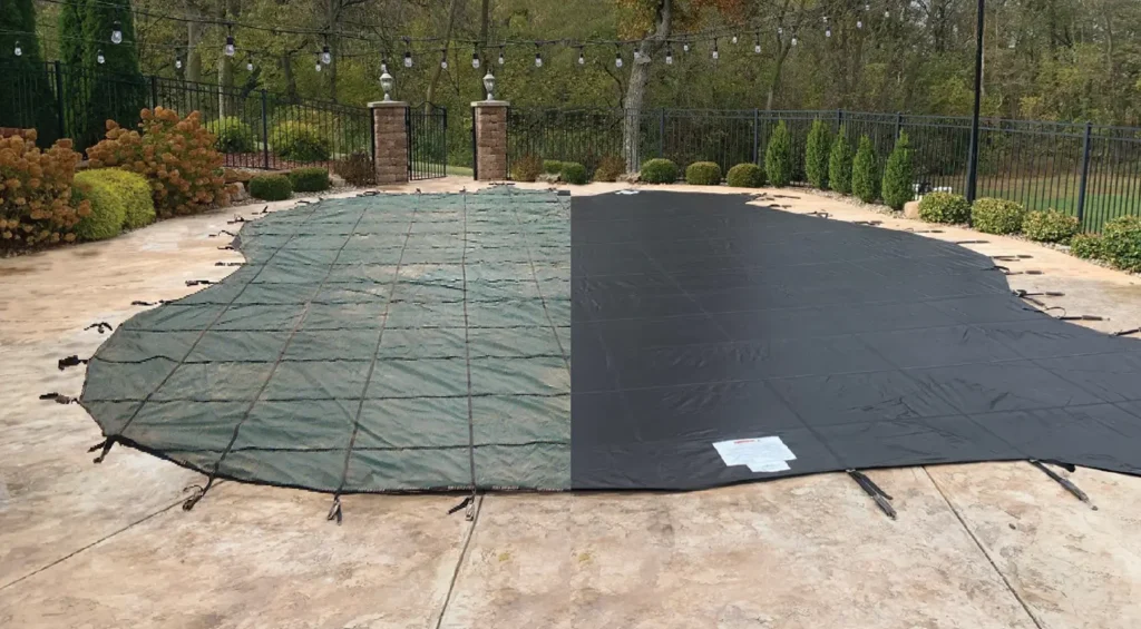 Backyard pool covered with a dark green mesh safety cover.