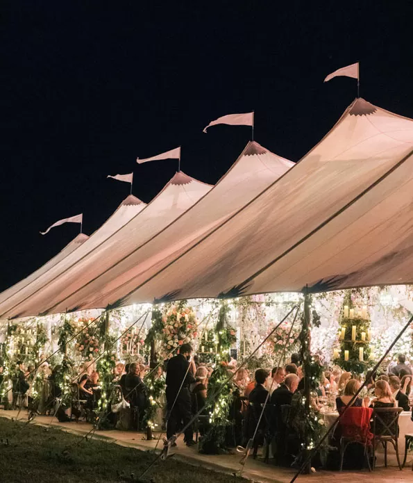 Large open-sided event tent with warm lighting at night.