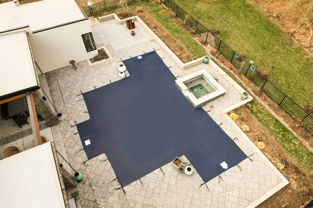 Overhead view of dark blue pool cover – Aerial shot of a backyard pool with dark blue mesh cover.