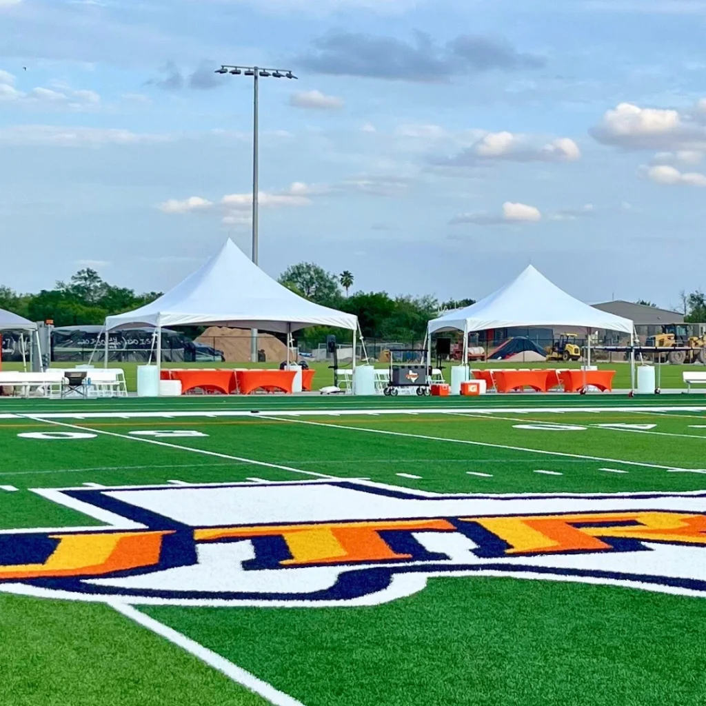 Large white frame canopy tent on grassy park area for events