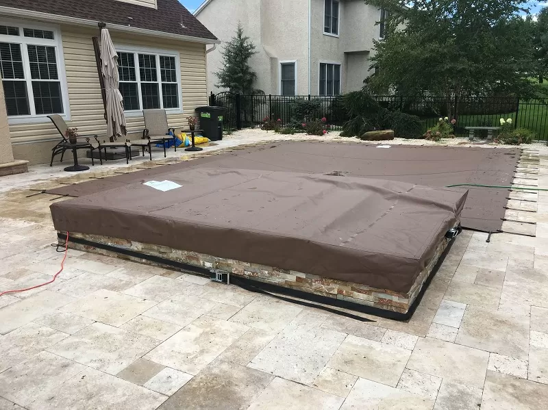 Brown solid pool cover fitted securely over a patio swimming pool.