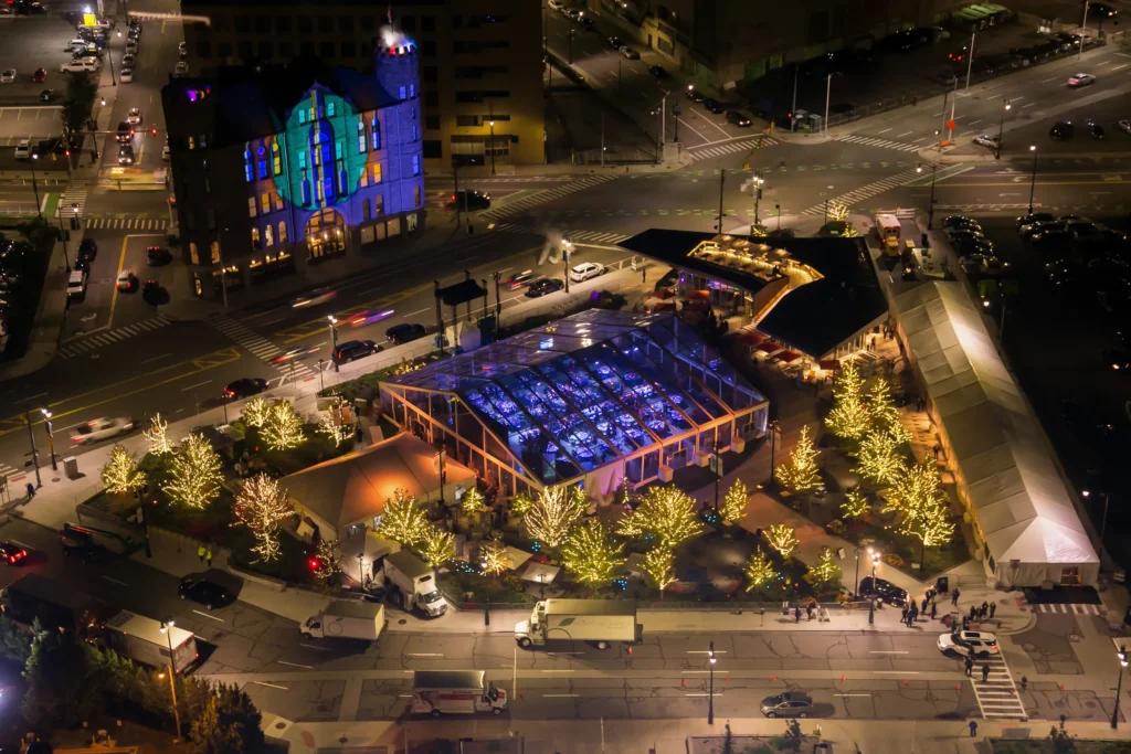 Aerial night view of illuminated sports complex with blue-lit court.