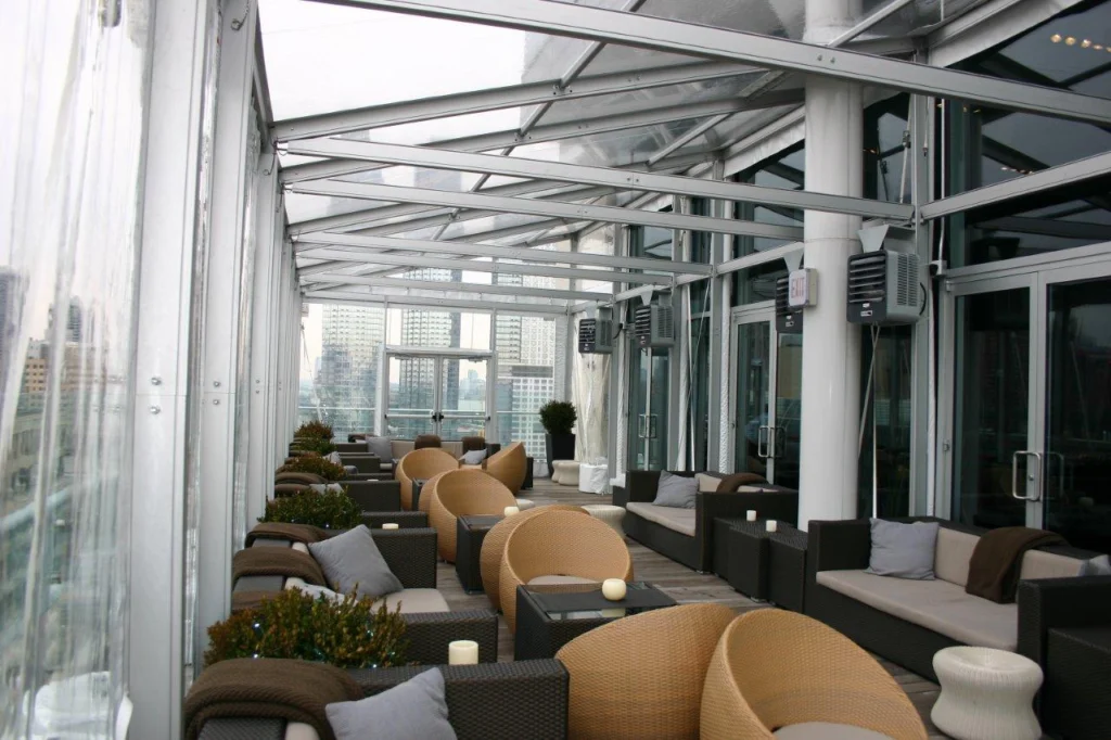 Glass-enclosed frame tent structure used for modern outdoor lounge area