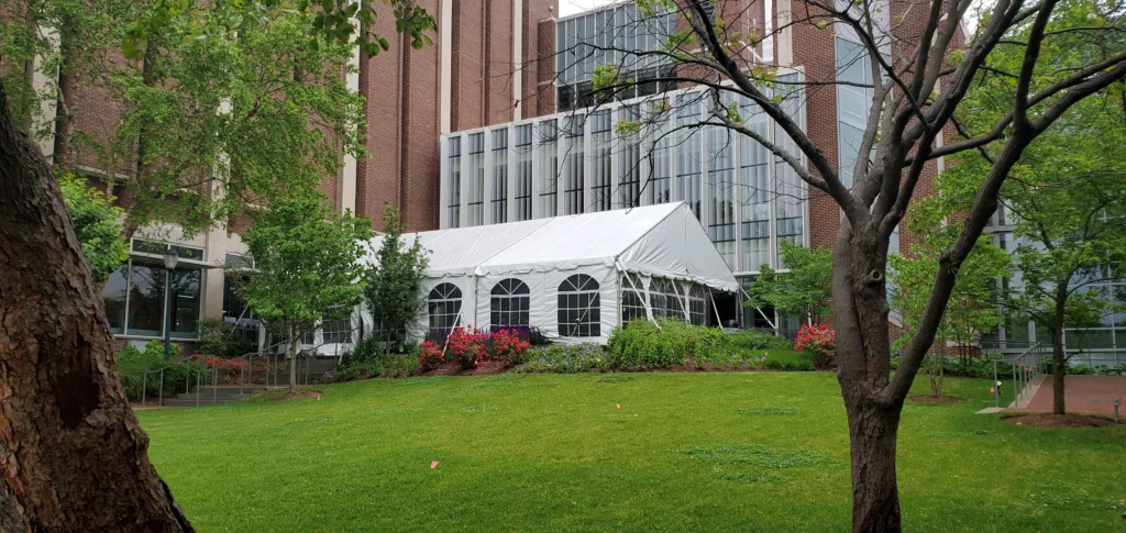White frame tent with arched windows set up on grass near building