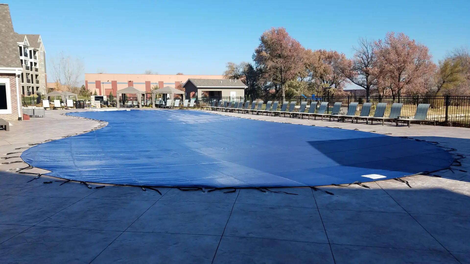 Blue solid pool cover – community pool with solid blue safety cover installed.