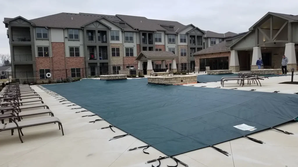 Apartment complex pool secured with a gray mesh safety cover.