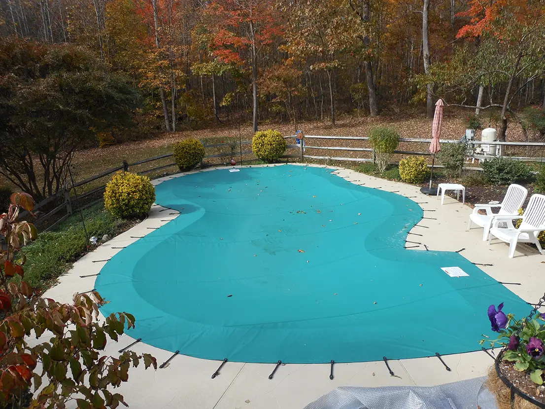 Irregularly shaped pool with turquoise water and surrounding stone patio.