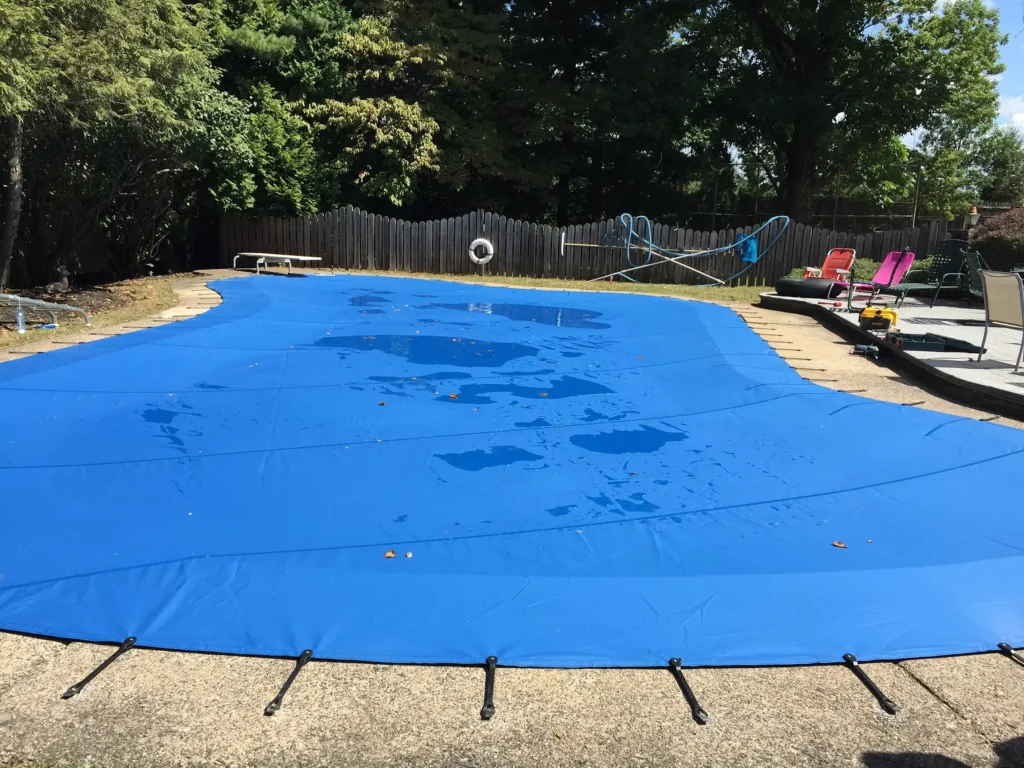 Bright blue pool safety cover tightly fitted over a rectangular pool.