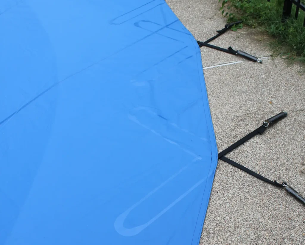 Blue safety pool cover stretched tightly across swimming pool deck.