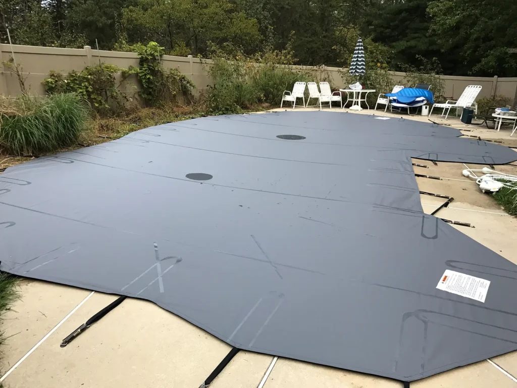 Gray pool cover installed on backyard swimming pool.