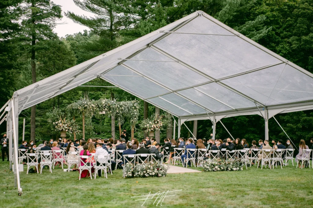 Open-sided tent with clear panels covering outdoor dining tables.