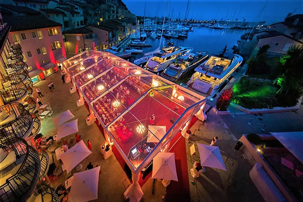 Clear top tent at marina hosting nighttime event with lighting