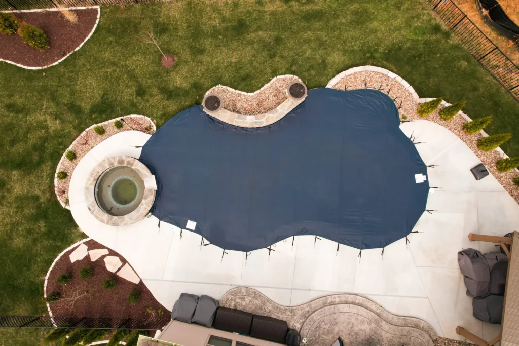 Custom-shaped pool cover installed on irregular backyard pool