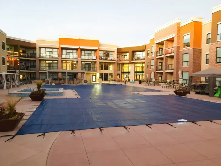 Blue pool safety cover fitted over resort swimming pool
