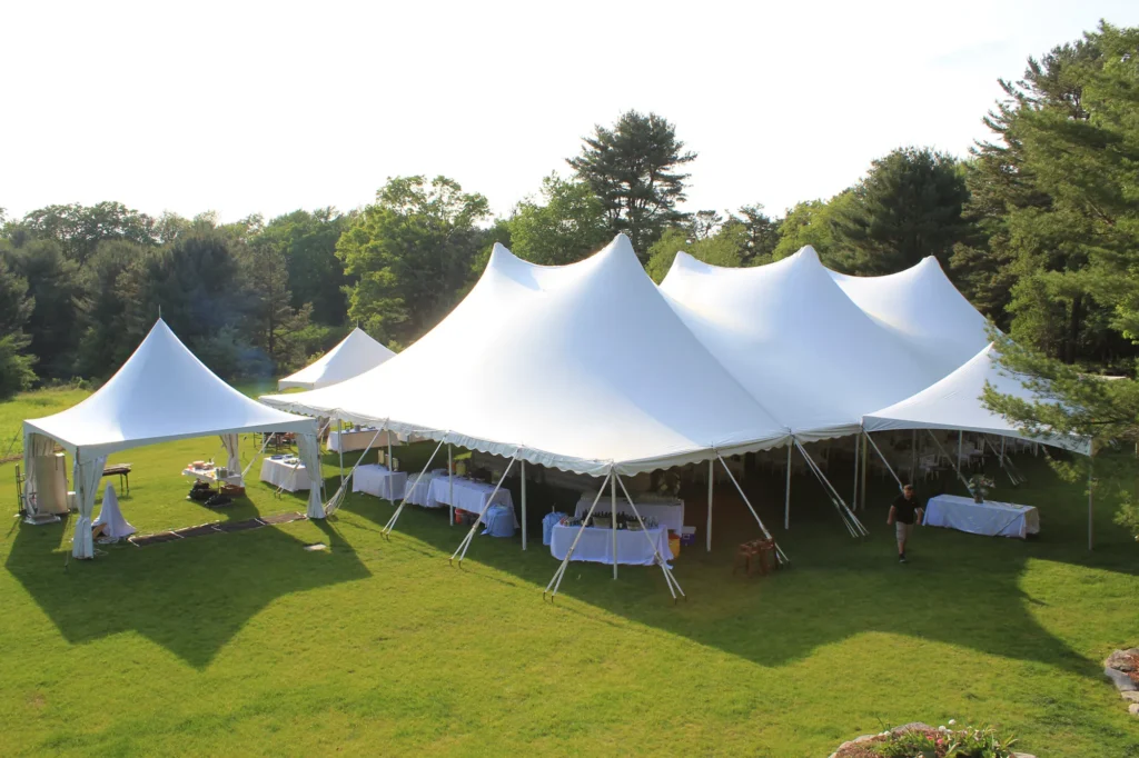 Large white sailcloth tent set up on a grassy event field.