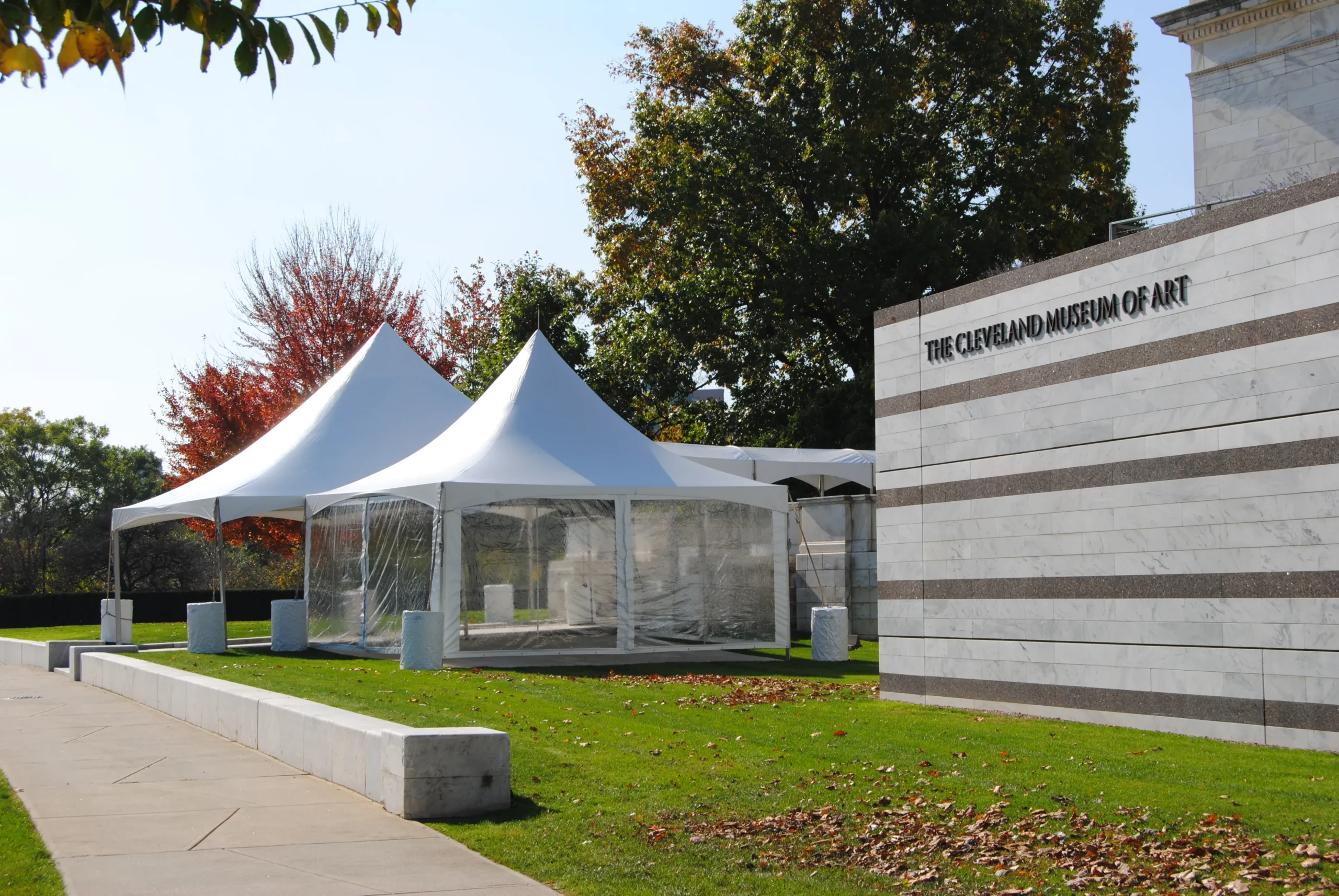 White marquee tent installed beside a modern building.