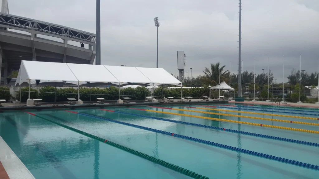 Large white event tent set up beside an outdoor swimming pool.