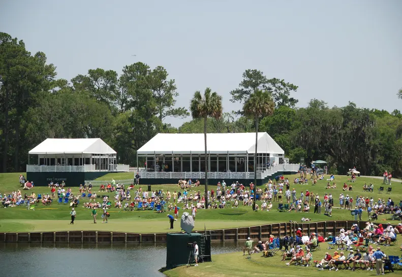 White frame tents installed on golf course for spectator seating