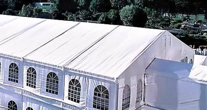 Large white frame tent with arched windows set up on grass