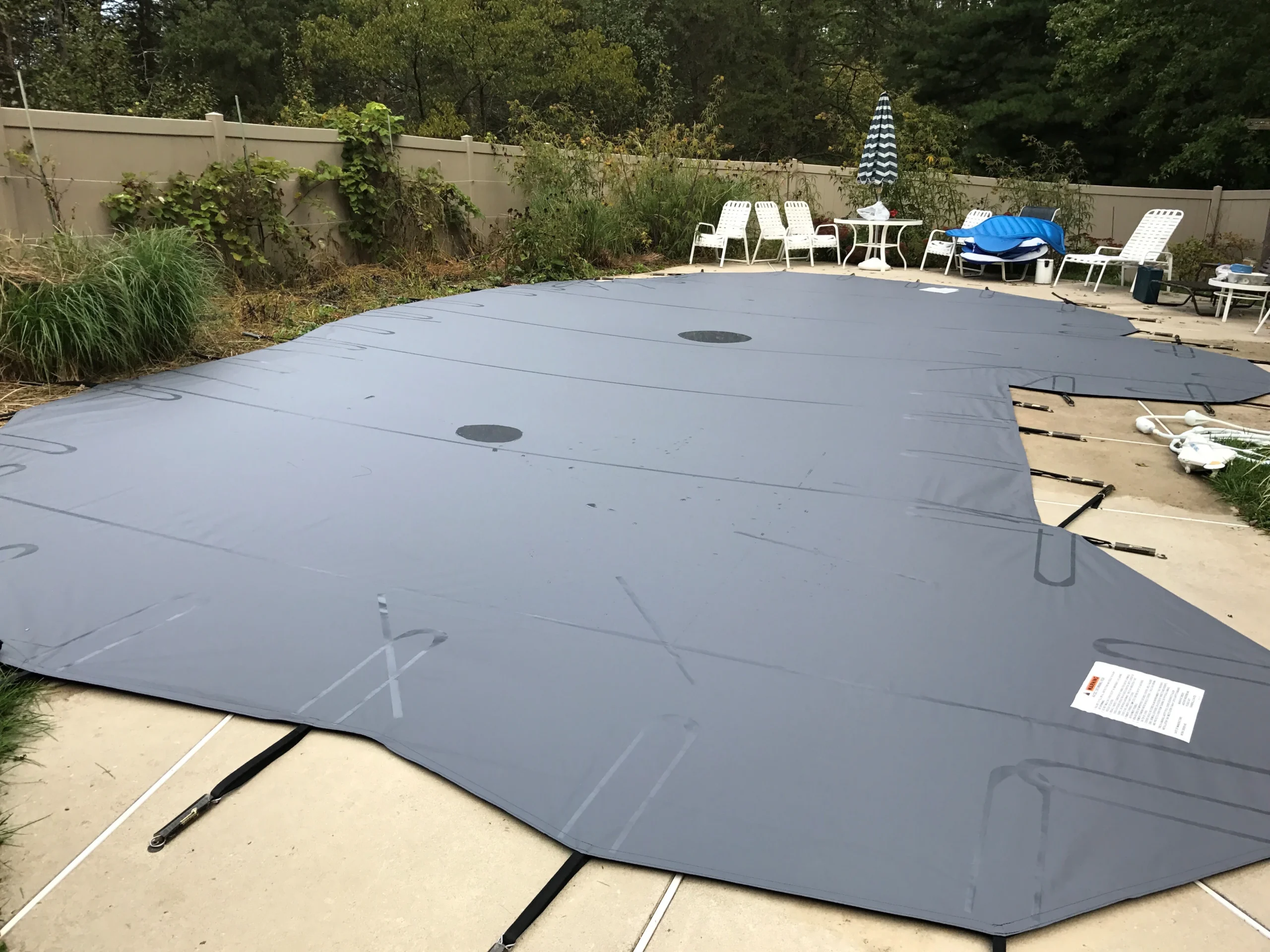 Dark gray safety pool cover secured across a large rectangular pool.