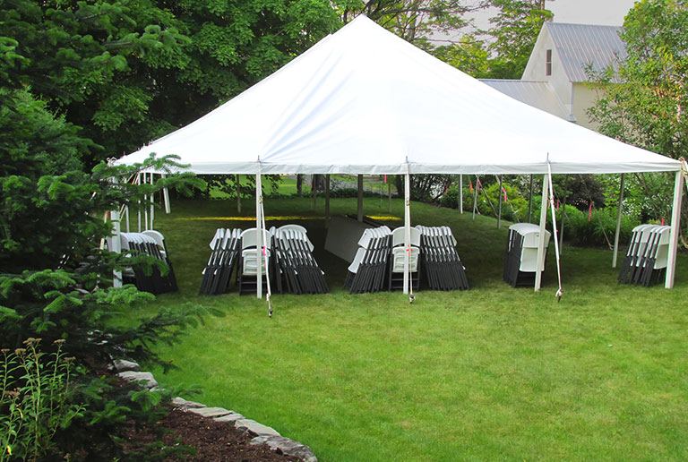 White frame tent with tables and chairs set up for an outdoor event.