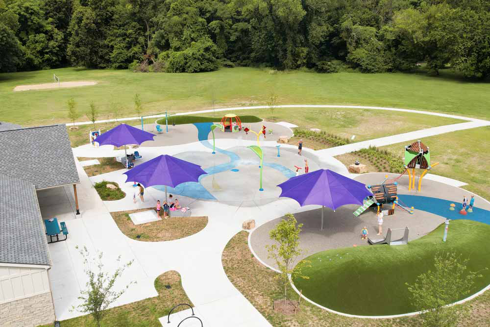 Small splash pad area with multiple purple shade umbrellas.