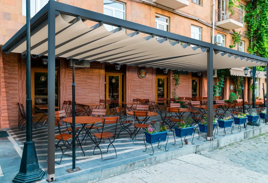 An Anchor motorized restaurant pergola providing shade and weather protection over an outdoor dining patio.