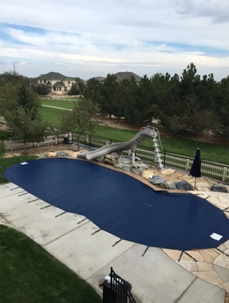 A heavy-duty safety mesh cover securing a modern fiberglass pool.