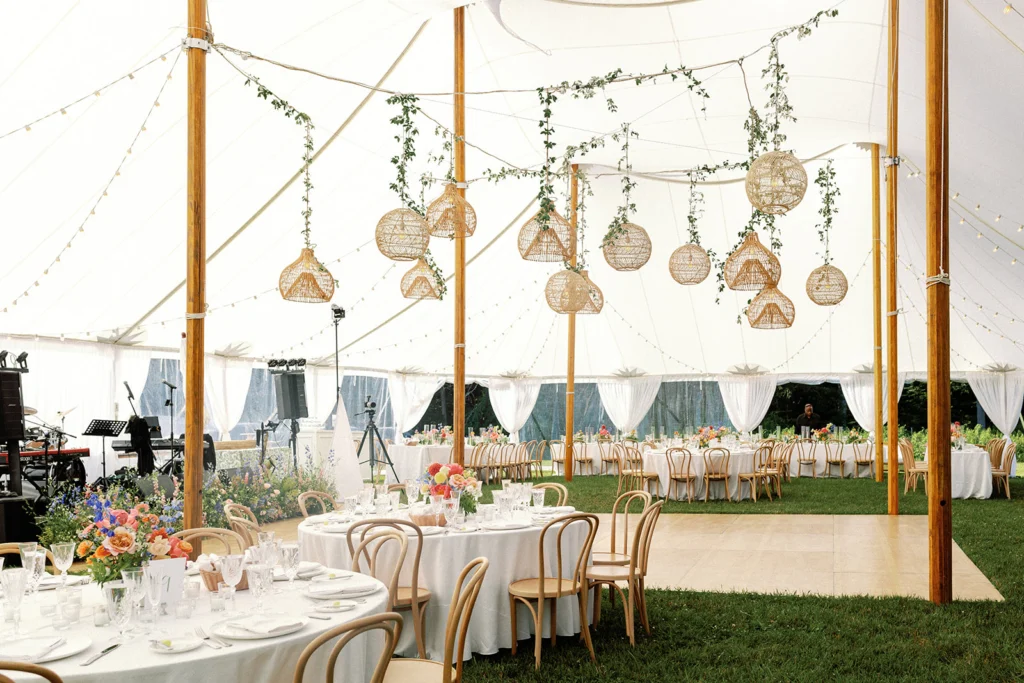 Interior of a large wedding pole tent featuring round tables and chairs set up for a sit-down dinner.
