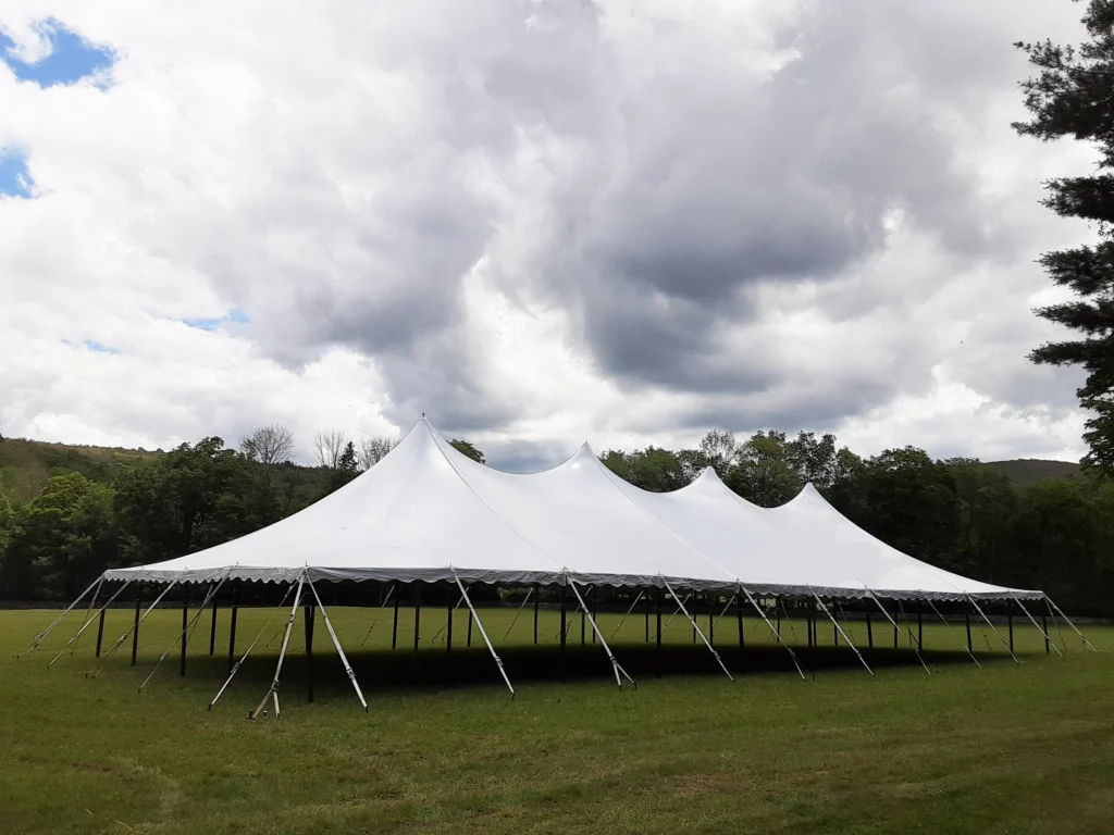 Exterior of a commercial frame tent set up on grass for a high-end corporate cocktail reception.