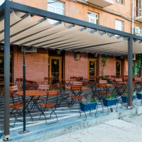 An Anchor motorized restaurant pergola providing shade and weather protection over an outdoor dining patio.