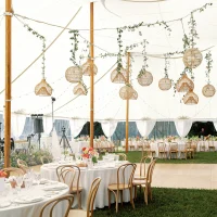 Interior of a large wedding pole tent featuring round tables and chairs set up for a sit-down dinner.