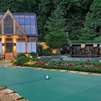 A custom safety cover installed over a clean backyard fiberglass pool.